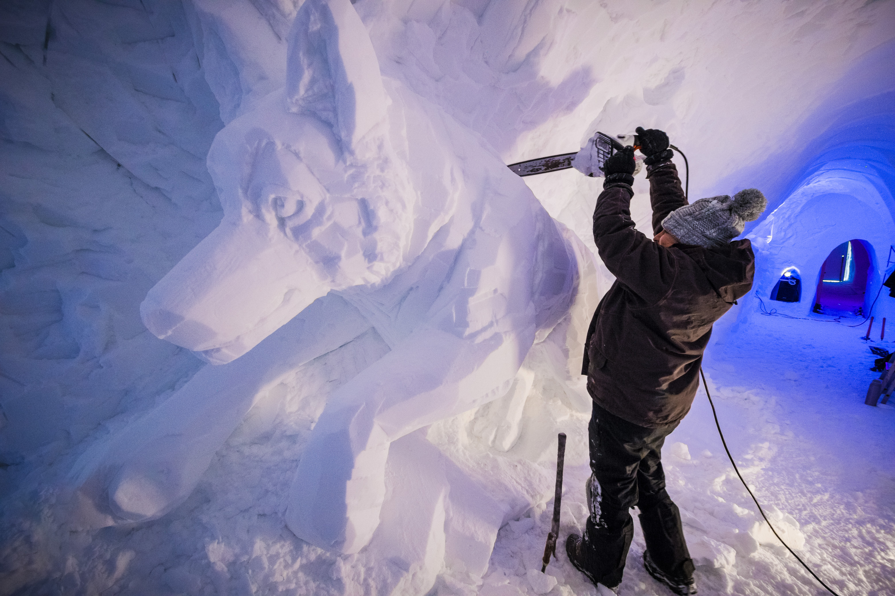 France, Auvergne-Rhône-Alpes, vallée de la Tarentaise, massif de la Vanoise, station de sports d'hiver Arcs 2000, Carina TORNATORIS sculpte un chien de traîneau dans la neige de la paroi du tunnel de la galerie de sculptures du village-igloo, lors de la saison hivernale 2017-2018 // France, Auvergne-Rhône-Alpes, Tarentaise valley, Vanoise massif, Arcs 2000 ski resort, Carina TORNATORIS sculpts a sled dog in the snow of the tunnel wall of the gallery with sculptures of igloo-village, during the winter season 2017-2018