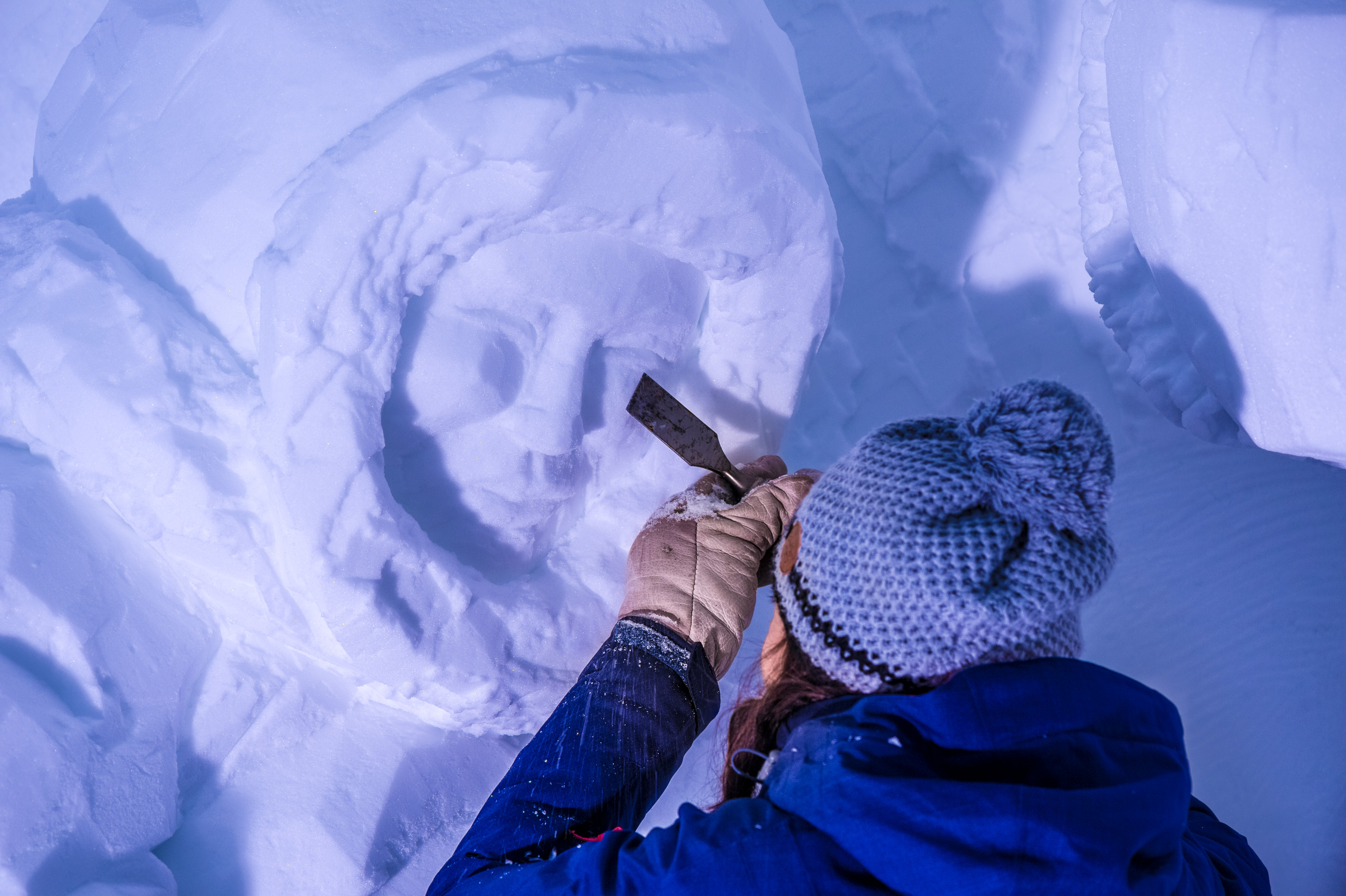 France, Auvergne-Rhône-Alpes, vallée de la Tarentaise, massif de la Vanoise, station de sports d'hiver Arcs 2000, Manon CHERPE sculpte une scène de pêche traditionnelle inuit dans la paroi de neige de la galerie de sculptures du village-igloo, lors de la saison hivernale 2017-2018 // France, Auvergne-Rhône-Alpes, Tarentaise valley, Vanoise massif, Arcs 2000 ski resort, Manon CHERPE sculpts a traditional Inuit fishing scene in the snow wall of the igloo village sculpture gallery, during the winter season 2017-2018